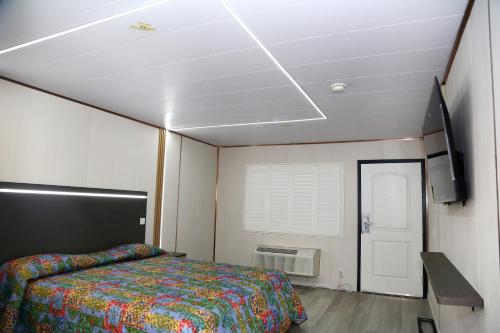 a bedroom with a bed and a tv and a ceiling at Airport Stay Motel in Ontario
