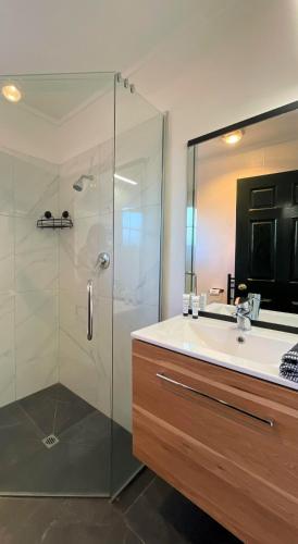 a bathroom with a glass shower and a sink at Colonial Motel in Twizel