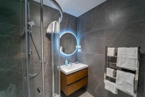 a bathroom with a sink and a shower with a mirror at Sunnyhills Viewside Town House in Auckland
