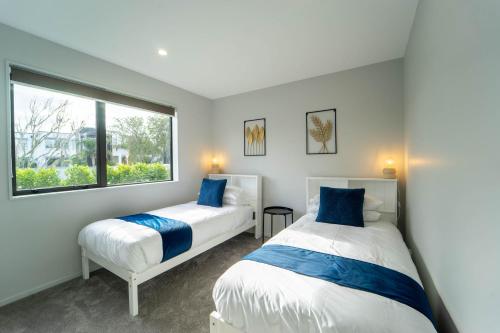 two beds in a room with a window at Sunnyhills Viewside Town House in Auckland