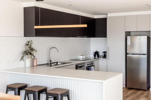 a kitchen with a white counter and stools in it at Little Island Apartments in Hobart