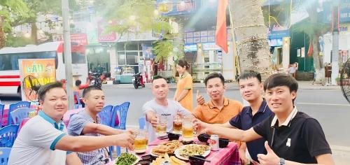 a group of people sitting at a table with food at Tung Quang Hotel in Cat Ba