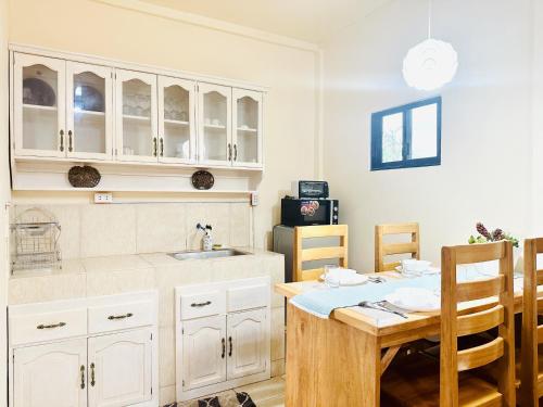 a kitchen with white cabinets and a wooden table at Paragua House in Taytay