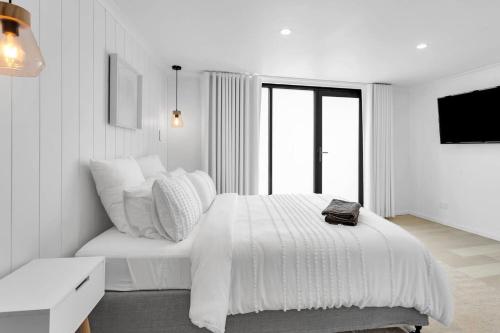 a white bedroom with a large bed and a tv at The Family Beachside Escape by Ready Set Stay - HOUSE & GUEST HOUSE in Rosebud