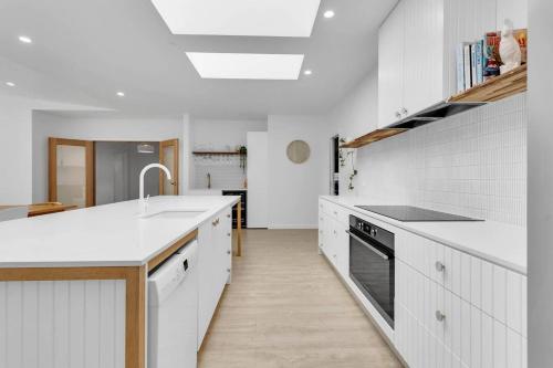 a white kitchen with white cabinets and a sink at The Family Beachside Escape by Ready Set Stay - HOUSE & GUEST HOUSE in Rosebud