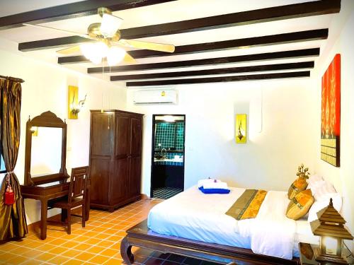 a bedroom with a bed and a desk and a ceiling fan at Boomerang Village Resort Kata in Kata Beach