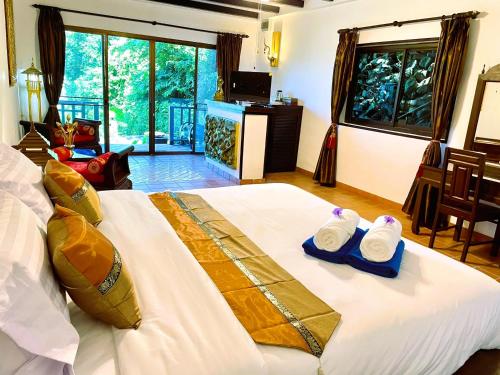 a bedroom with a bed with two towels on it at Boomerang Village Resort Kata in Kata Beach