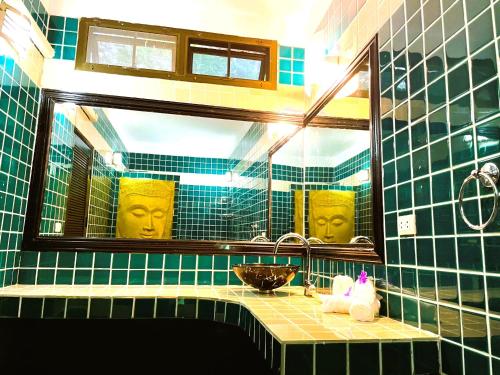 a green tiled bathroom with a sink and a mirror at Boomerang Village Resort Kata in Kata Beach
