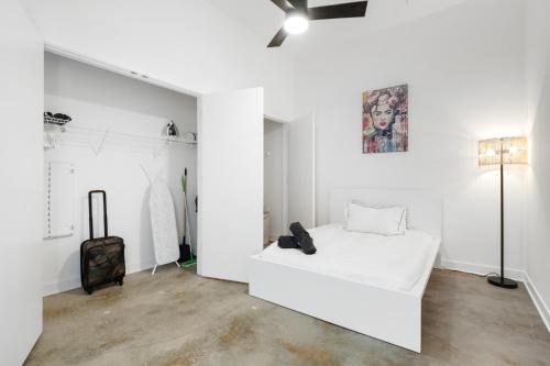 a white room with a bed and a suitcase at Ballpark Luxury Loft steps from Arch in Saint Louis