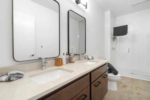 a bathroom with two sinks and a large mirror at Ballpark Luxury Loft steps from Arch in Saint Louis