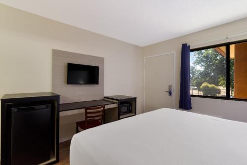 a bedroom with a bed and a desk and a tv at Rodeway Inn Livermore in Livermore