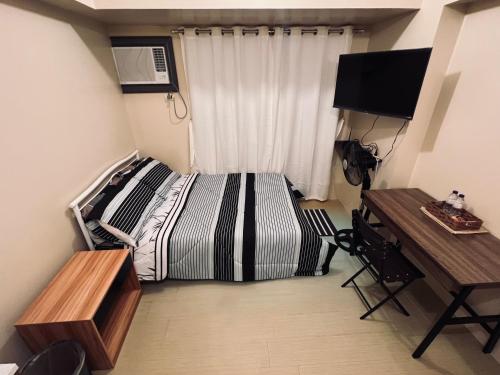 Dormitorio con cama, escritorio y TV en C Comfortable Avida Room, en Iloilo City