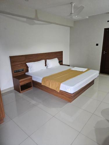 Schlafzimmer mit einem großen Bett mit einem Kopfteil aus Holz in der Unterkunft Uptown Inn in Ernakulam