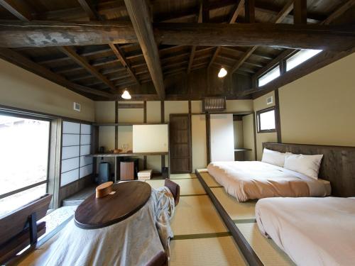 1 dormitorio con 2 camas y mesa. en kominka neri（古民家煉り）, en Miyawaka