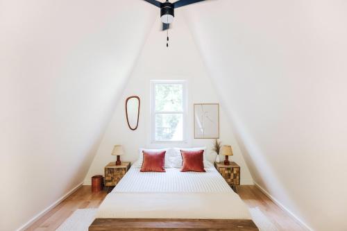 um quarto com uma cama branca e 2 almofadas vermelhas em Victoria´s forest House em Roatan