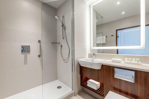 a bathroom with a shower and a sink and a mirror at Courtyard by Marriott Reykjavik Keflavik Airport in Keflavík