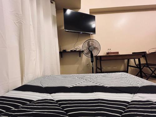 um quarto com uma cama e uma televisão de ecrã plano em C Comfortable Avida Room em Iloilo City