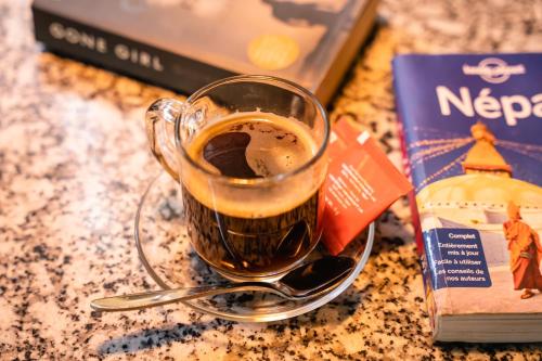 a cup of coffee on a table next to a book at Kwabahal Boutique Hostel in Kathmandu