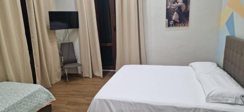 a bedroom with a white bed and a television at B&B Mongibello in Viagrande