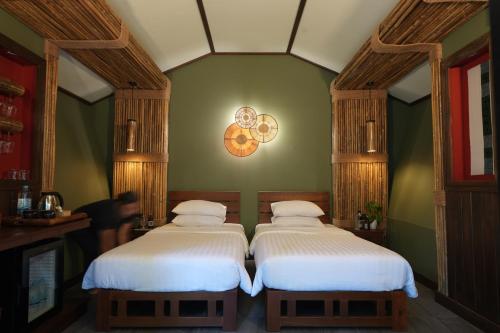 two beds in a room with a person standing between them at Nampien Yorla Pa in Ban Nôn