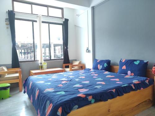 ein Schlafzimmer mit einem Bett mit blauer Decke und einem Fenster in der Unterkunft Hotel Norbuling in Dirang Dzong