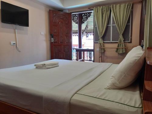 ein großes weißes Bett mit einem TV an der Wand in der Unterkunft Ben Guesthouse in Chiang Rai