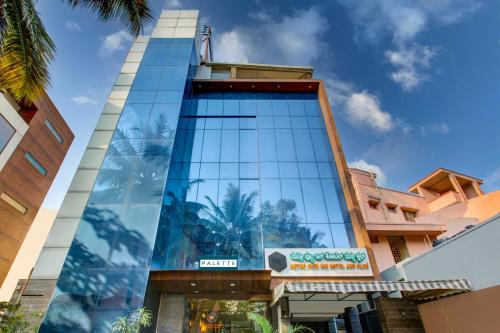een hoog glazen gebouw met een bord erop bij Townhouse Oak JVH hotel (Next to Mysore Road Metro Station) in Bangalore