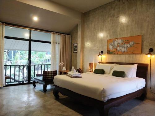 a bedroom with a large bed and a large window at Arun Rawee อรุณ รวี in Chiang Mai