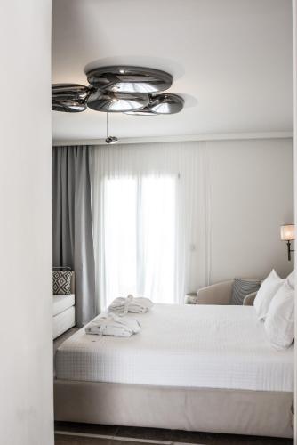 a bedroom with a white bed with a ceiling fan at Νumi Boutique Hotel in Mýkonos City