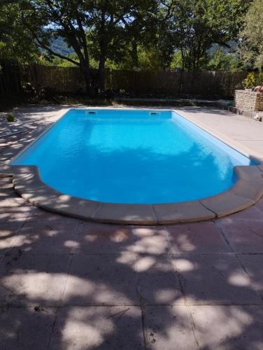 a swimming pool with blue water in a backyard at Chambre d’hôtes l’Orange Bleue in Rustrel