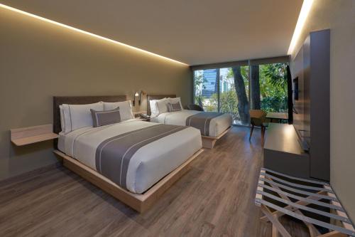 a hotel room with two beds and a television at City Express Plus by Marriott Guadalajara Providencia in Guadalajara