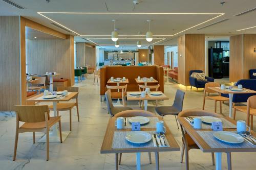 a restaurant with tables and chairs and a cafeteria at City Express Plus by Marriott Guadalajara Providencia in Guadalajara