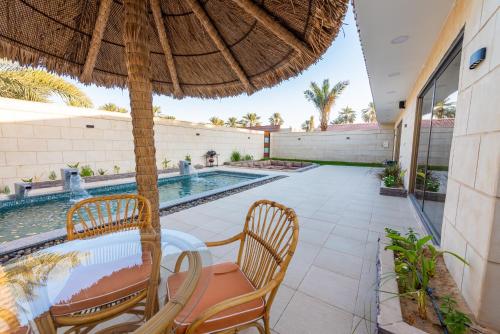 a patio with a table and chairs and an umbrella at منتجع كالوتارا in Banī Ma‘n