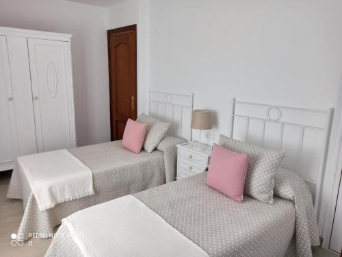 2 camas con almohadas rosas en una habitación en Casa La Loma en Archidona en Málaga