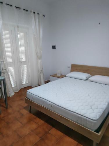 a bed in a room with white walls and windows at La casa di Rosy in Porto Santo Stefano