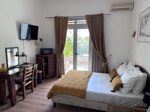 a bedroom with a bed and a desk and a television at Hôtel Résidence Le Phoenix in Saint-Pierre
