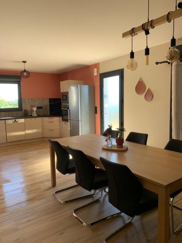a kitchen and dining room with a wooden table and chairs at Gîtes Rozanna avec accès détente SPA JACUZZI in Saint-Jean-de-la-Rivière
