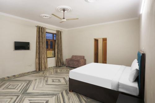 een hotelkamer met een bed en een stoel bij OYO Flagship 85830 Ann's Cottage in Faridabad