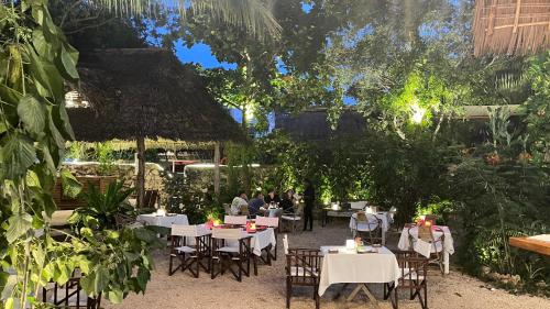 a restaurant with tables and chairs in a garden at Atii Garden Bungalows in Nungwi