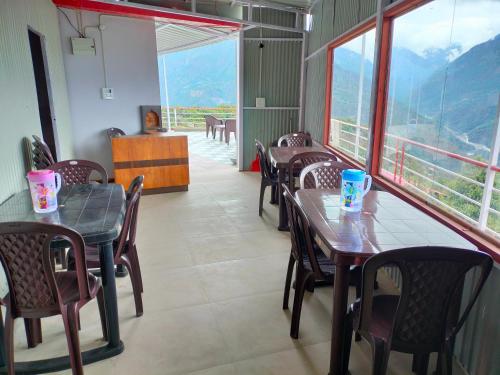 Gupta KāshiにあるShree Neelkanth Resortのテーブルと椅子、大きな窓のあるレストラン