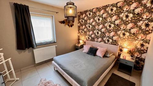 a bedroom with a bed with a floral wall at BeCosy appartement 2 chambres et jardin 6 pers in Mons