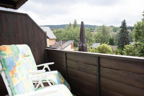 a balcony with a chair and an umbrella at Landhotel Jägerhof in Bischofsgrün