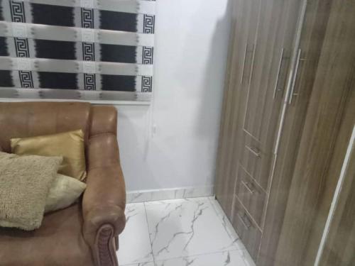 uma casa de banho com uma cadeira castanha e um chuveiro em Home of peace, joy and rest em Benin City