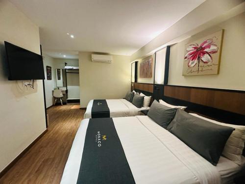 um quarto de hotel com duas camas e uma televisão em Monaco Hotel em Cyberjaya