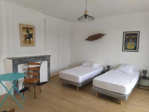 Cette chambre comprend deux lits, une table et une cheminée. dans l'établissement Maison Chez Catherine, à Baix