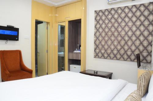 a bedroom with a bed and a chair and a television at CRYTSAL RESIDENCY in Rānchī