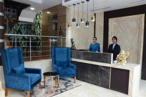 two men standing at a reception desk with blue chairs at CRYTSAL RESIDENCY in Rānchī