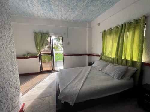 1 dormitorio con 1 cama con cortina verde en Beach Road Apartments en Matabungkay