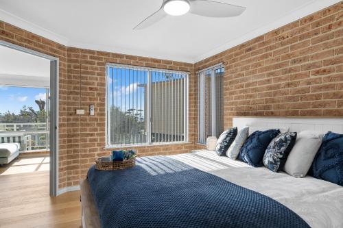 a bedroom with a bed and a brick wall at Bella Vista: Ocean views a short stroll to beach. in Mollymook