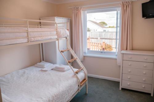 a bedroom with a bunk bed and a window at Wheelchair accessible 2 bedroom bungalow Dog Friendly in Brixham